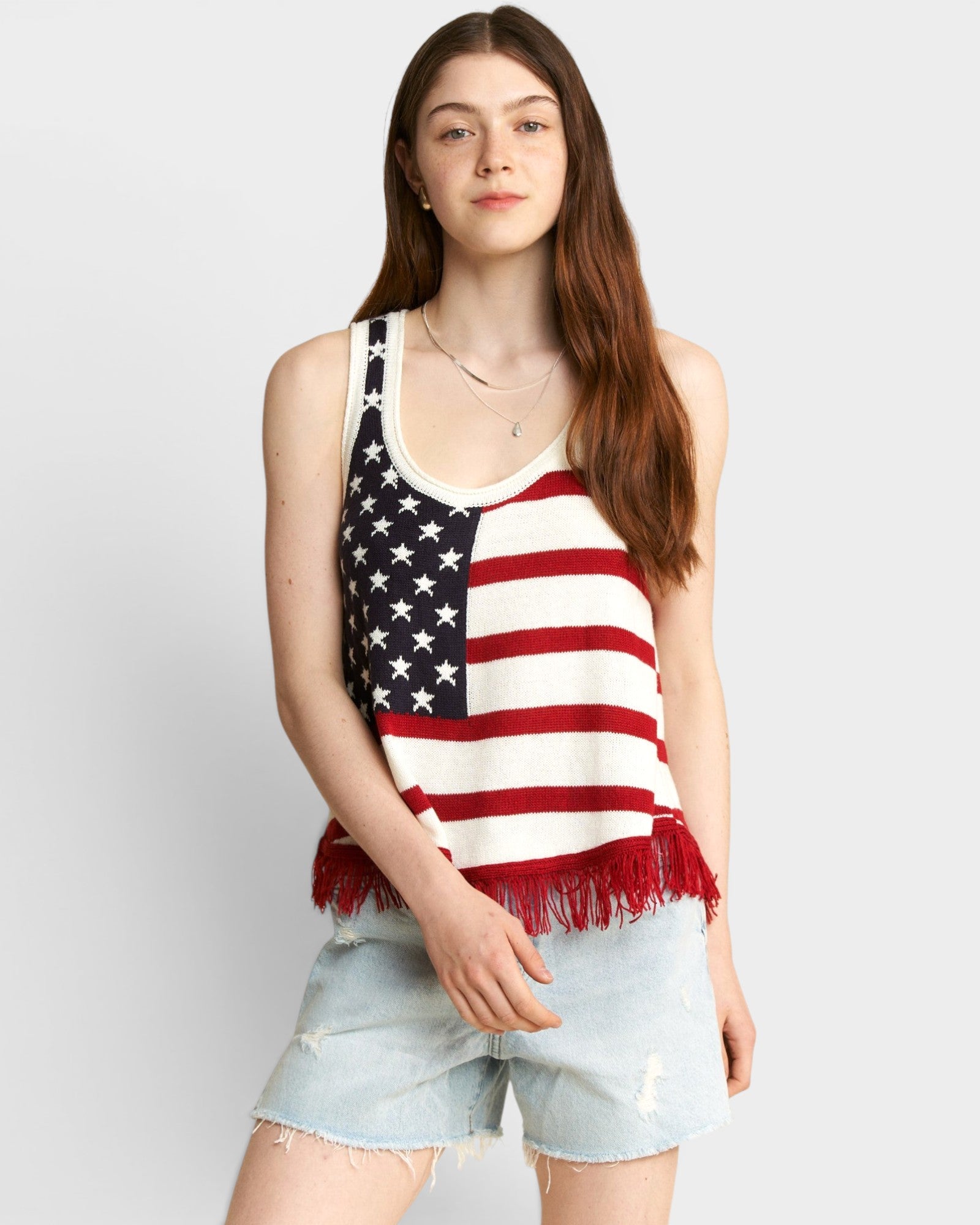 Person wearing a tank top with an American flag design on a plain background
