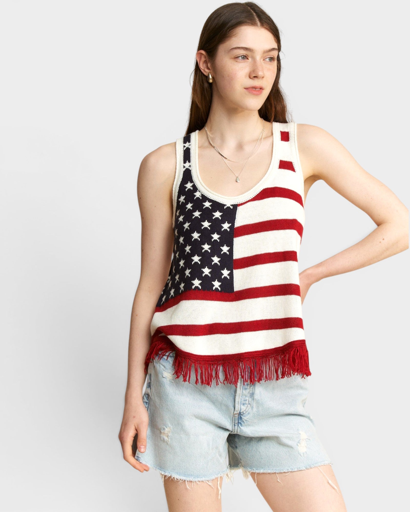 Woman wearing a tank top with an American flag design on a plain background