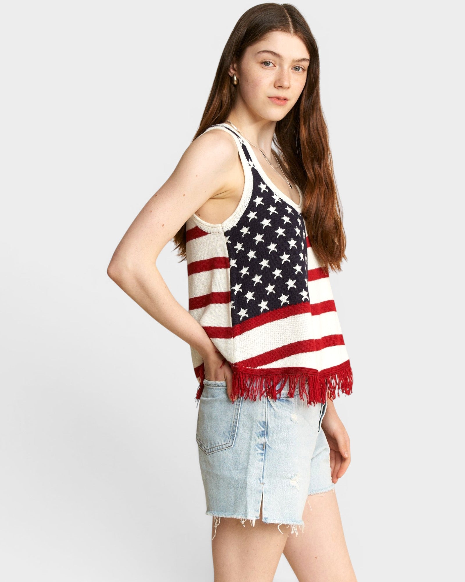 Woman wearing a tank top with an American flag design on a plain background