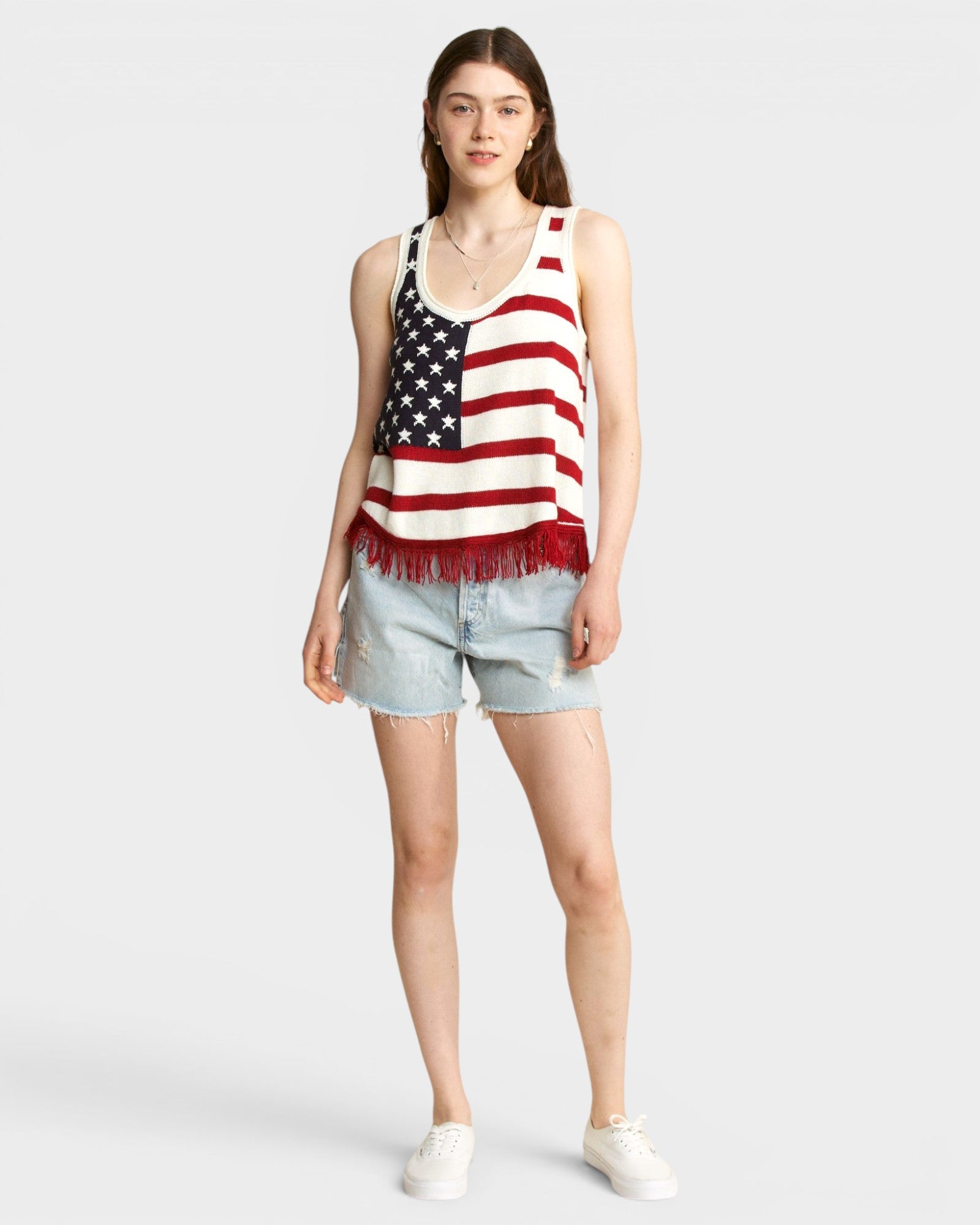 Woman wearing a tank top with an American flag design on a plain background