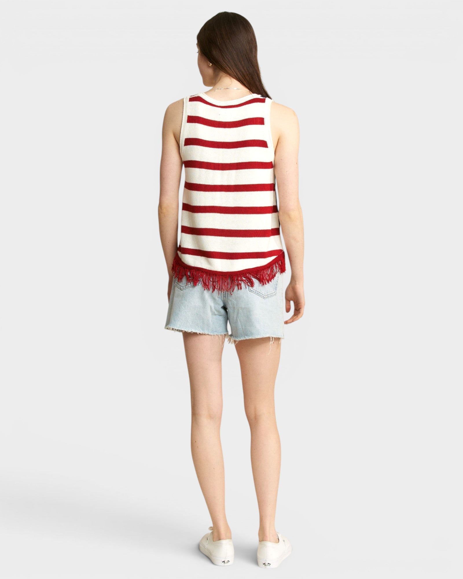 Person wearing a red and white striped tank top and denim shorts on a light gray background