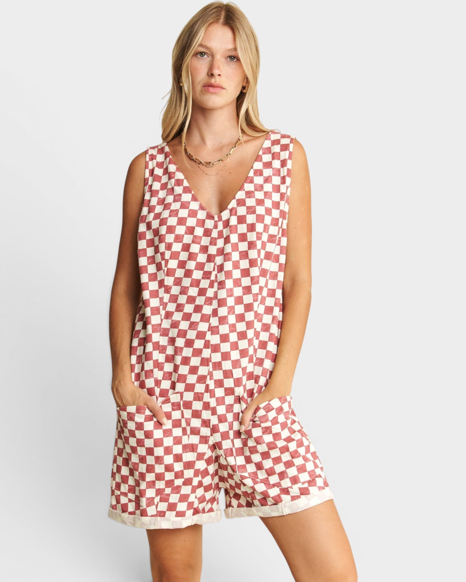 Woman wearing a red and white checkered romper on a light gray background