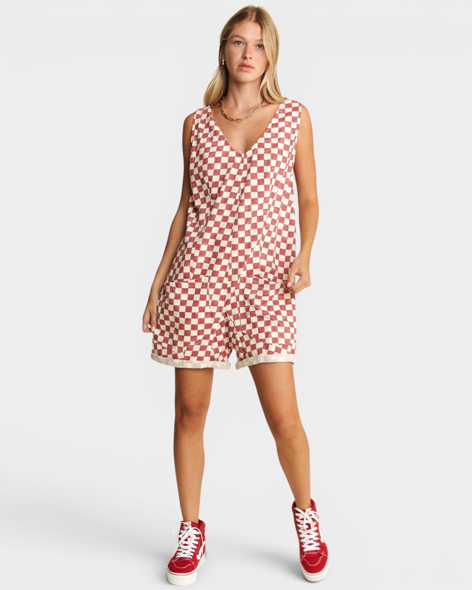Woman wearing a red and white checkered dress with red high-top sneakers on a white background