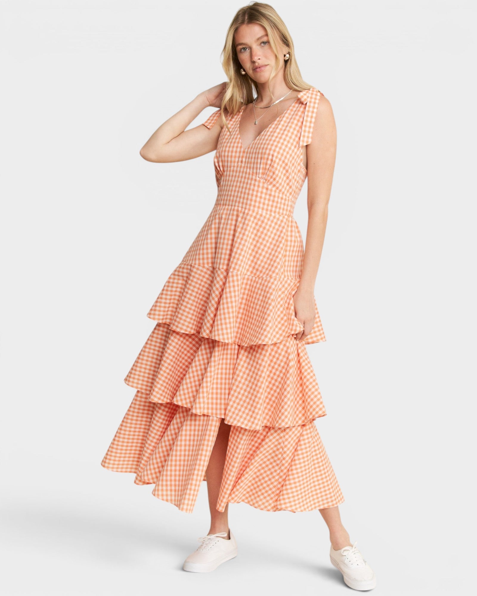 Woman wearing a tiered orange checkered dress on a white background