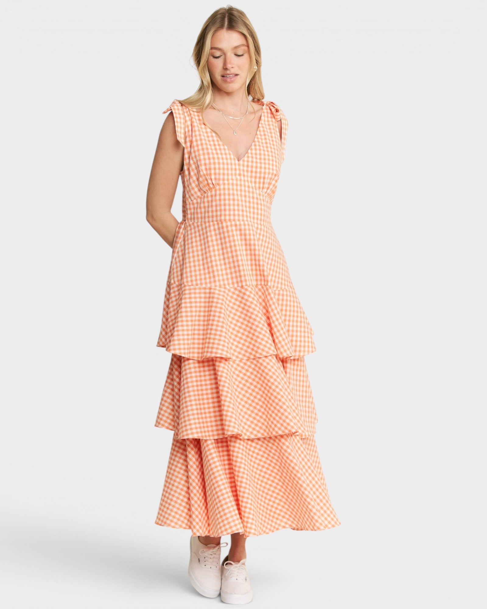 Woman wearing a peach-colored checkered dress on a white background