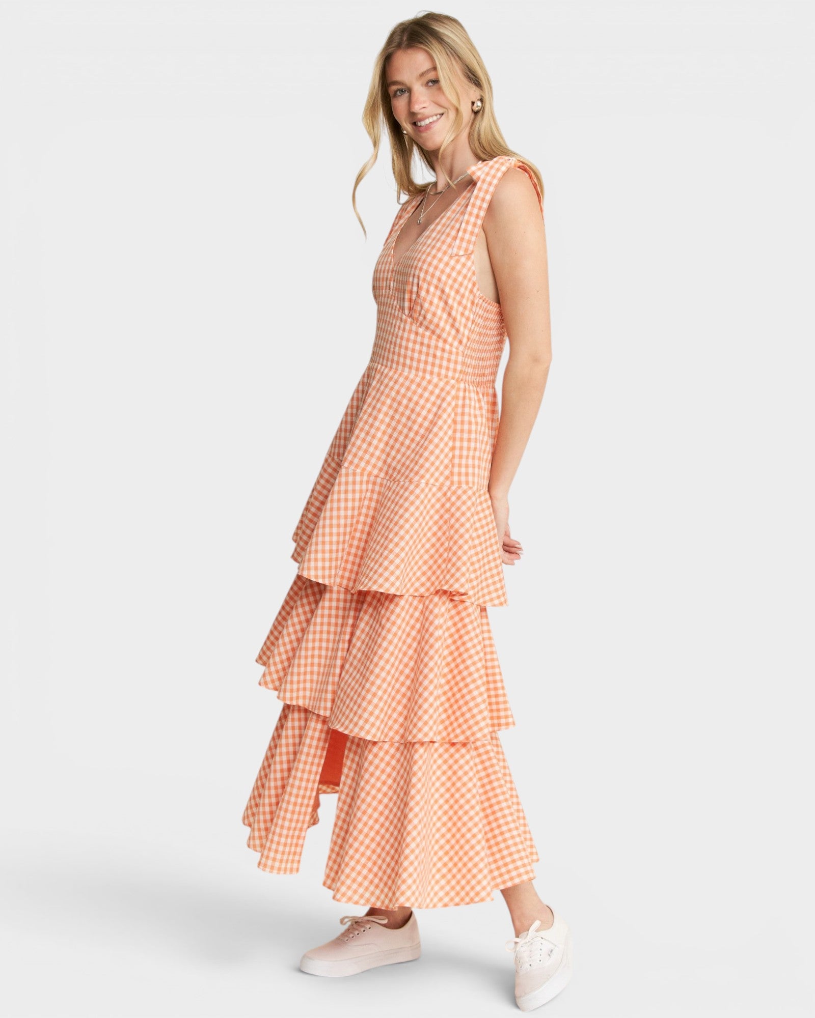Woman wearing a tiered, checkered dress on a white background