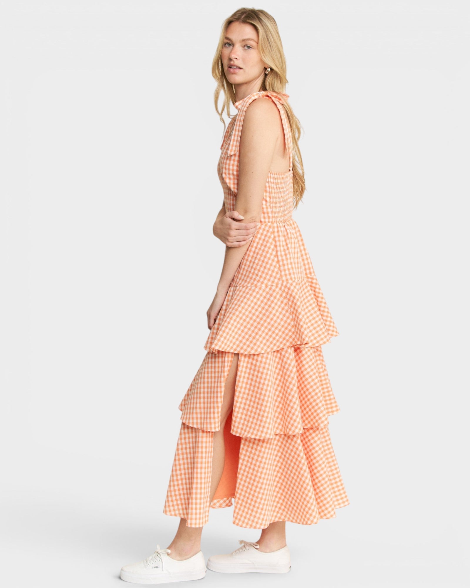 Woman wearing a peach-colored checkered dress on a white background