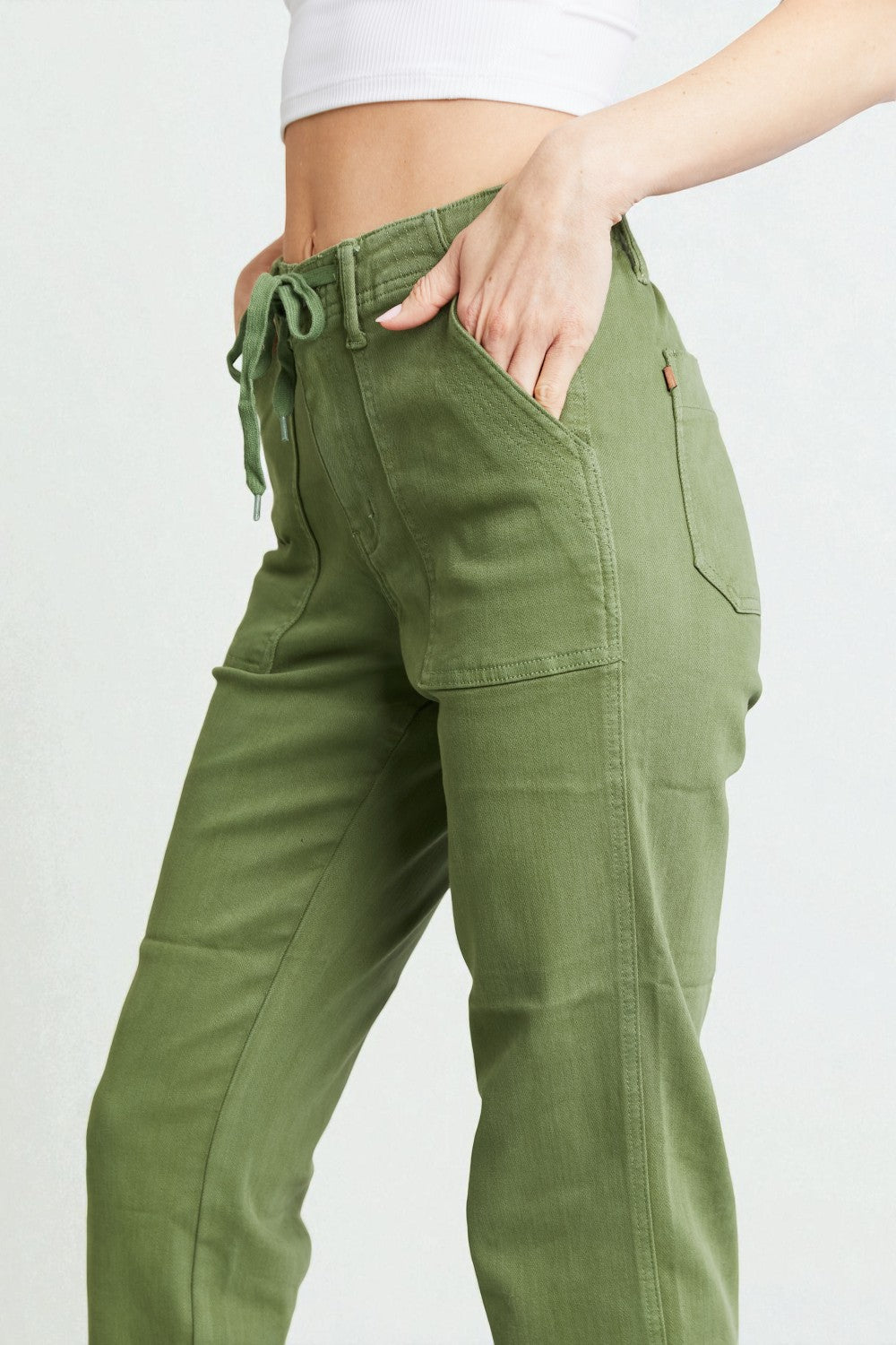 Green cargo pants worn by a person on a white background