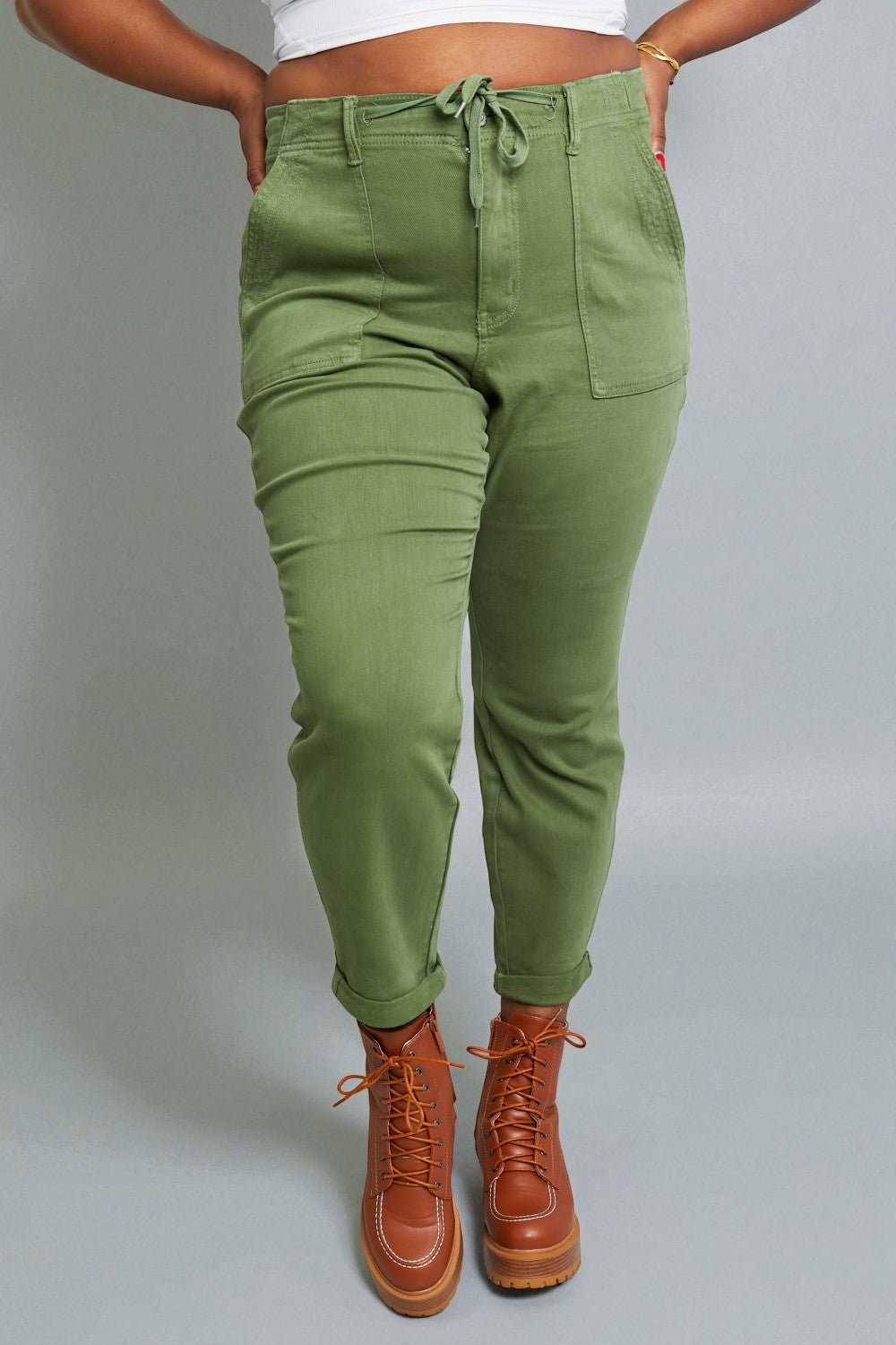 Person wearing green pants and brown boots on a gray background