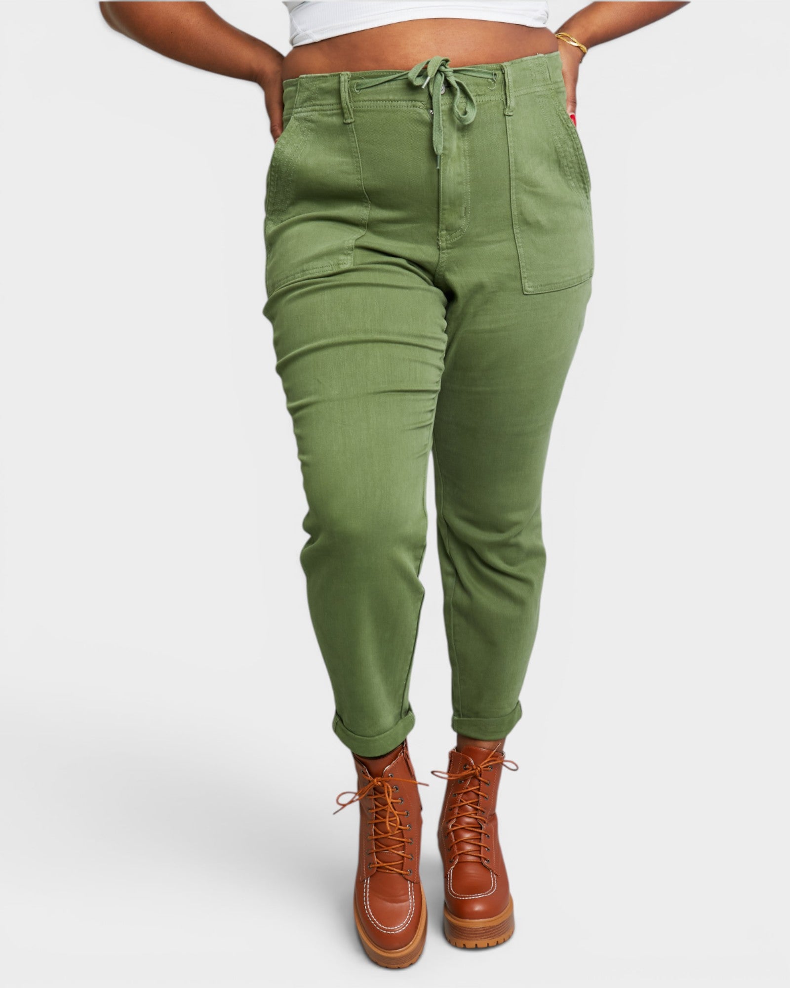 Person wearing green pants and brown boots on a white background