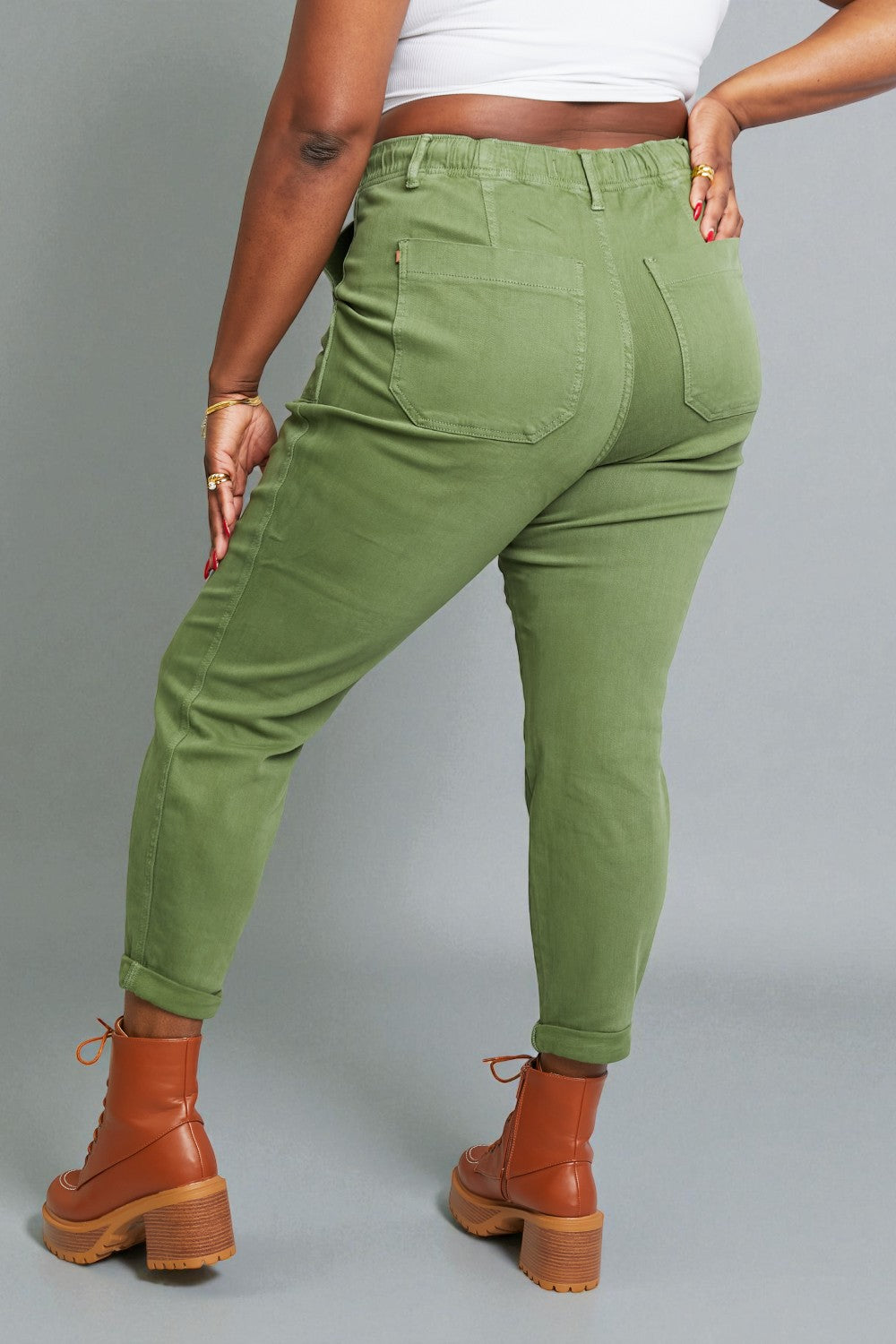 Person wearing green pants and brown boots on a gray background