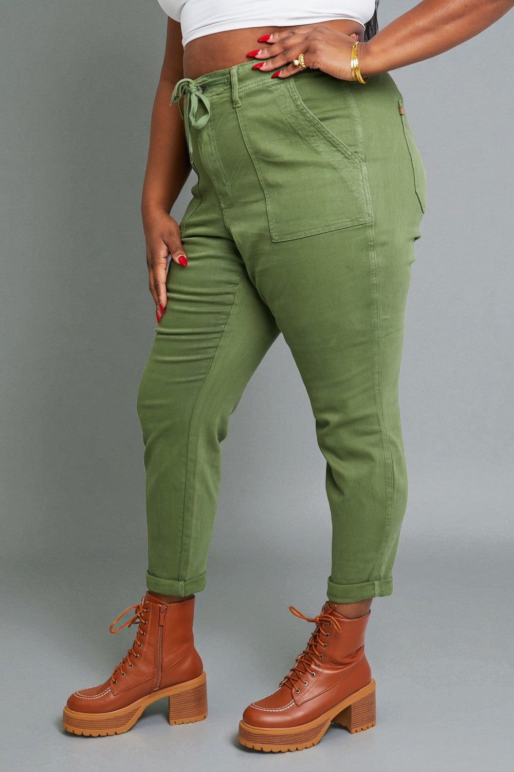 Person wearing green pants and brown boots on a gray background