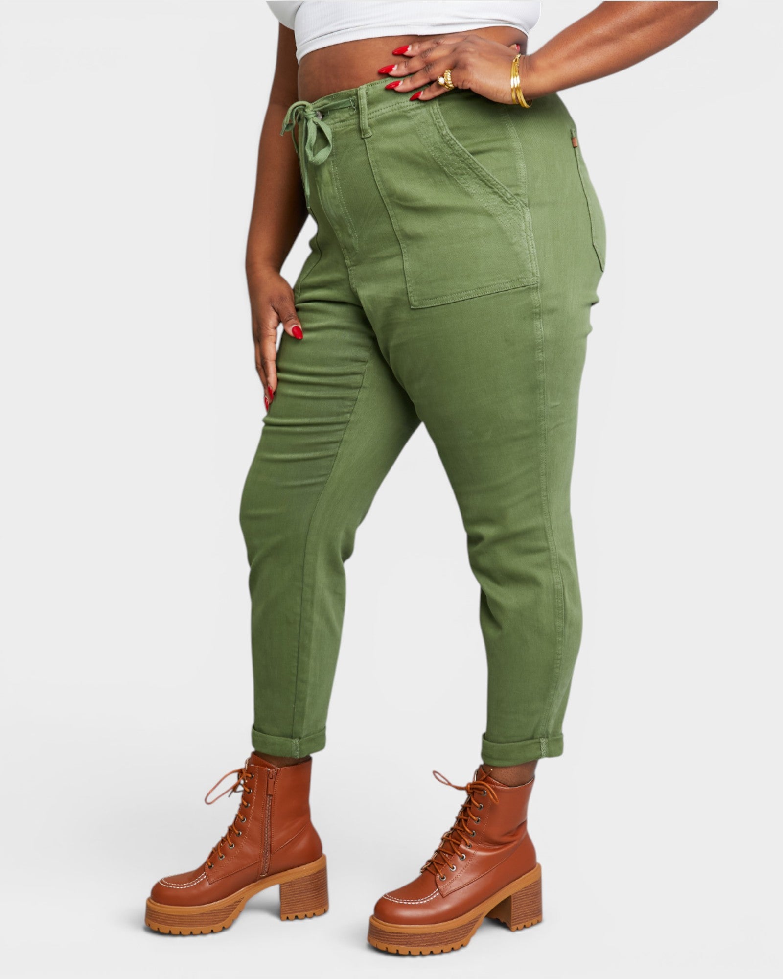Person wearing green cargo pants and brown boots on a white background
