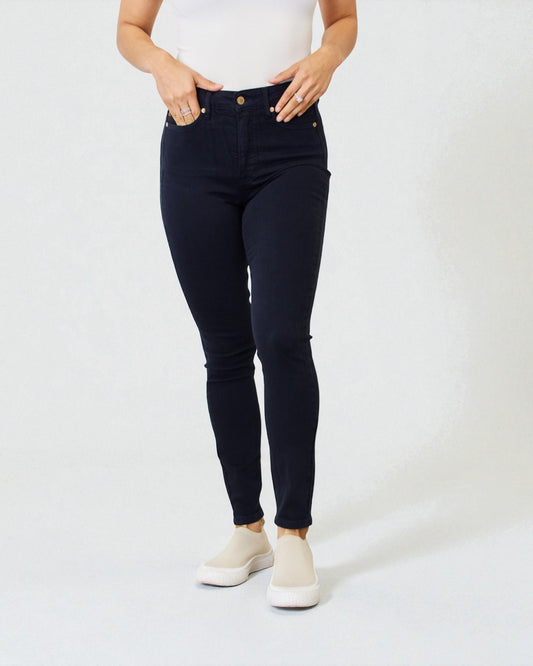 Person wearing black jeans and white sneakers on a white background