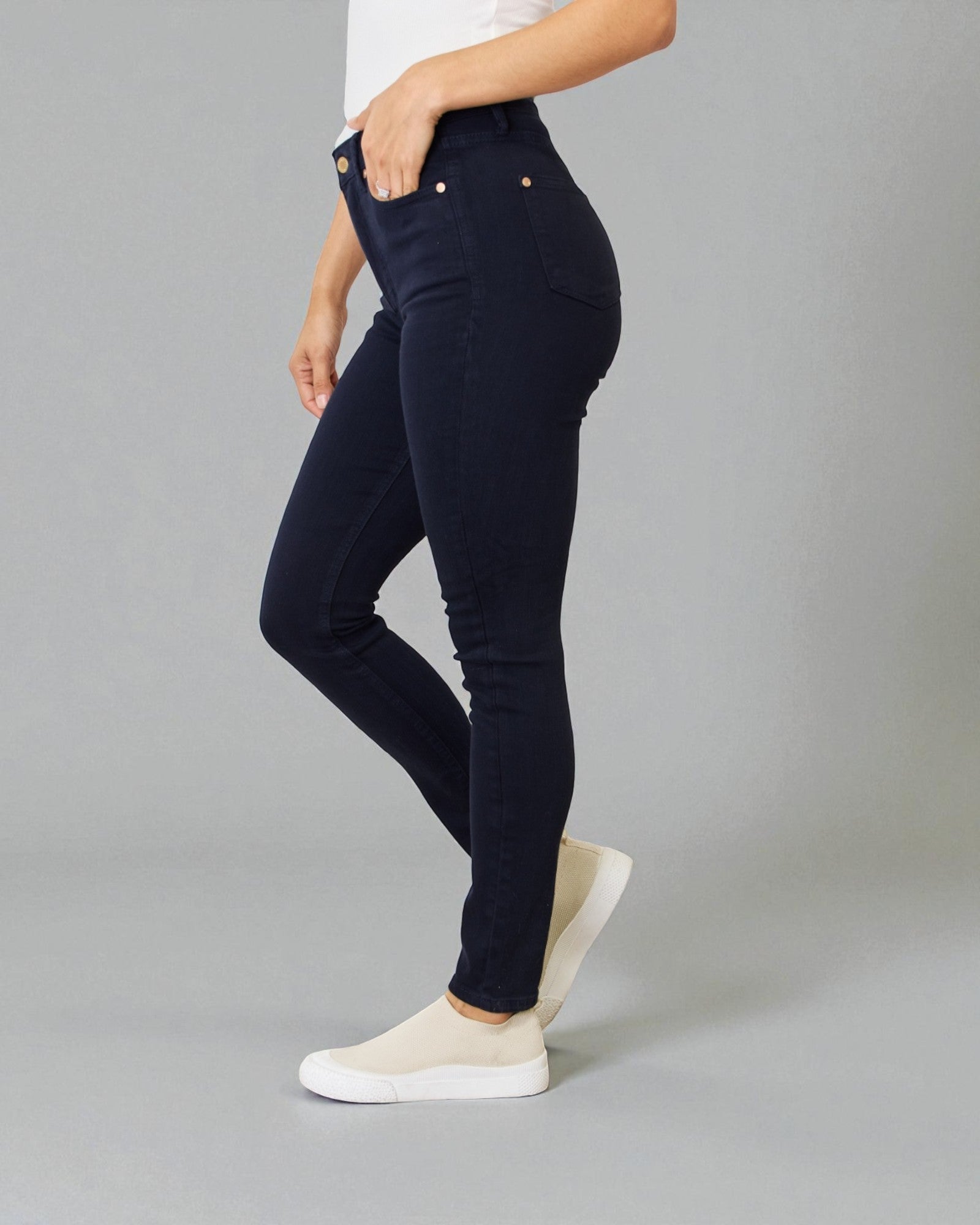 Person wearing navy blue jeans on a gray background