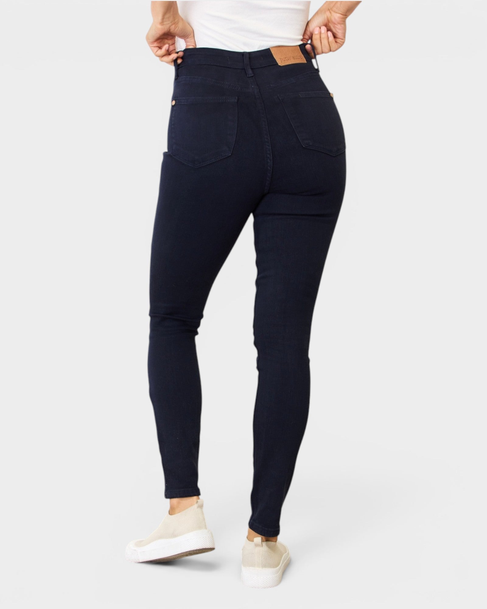 Person wearing dark blue jeans on a white background