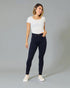 Woman wearing navy jeans and a white top on a gray background