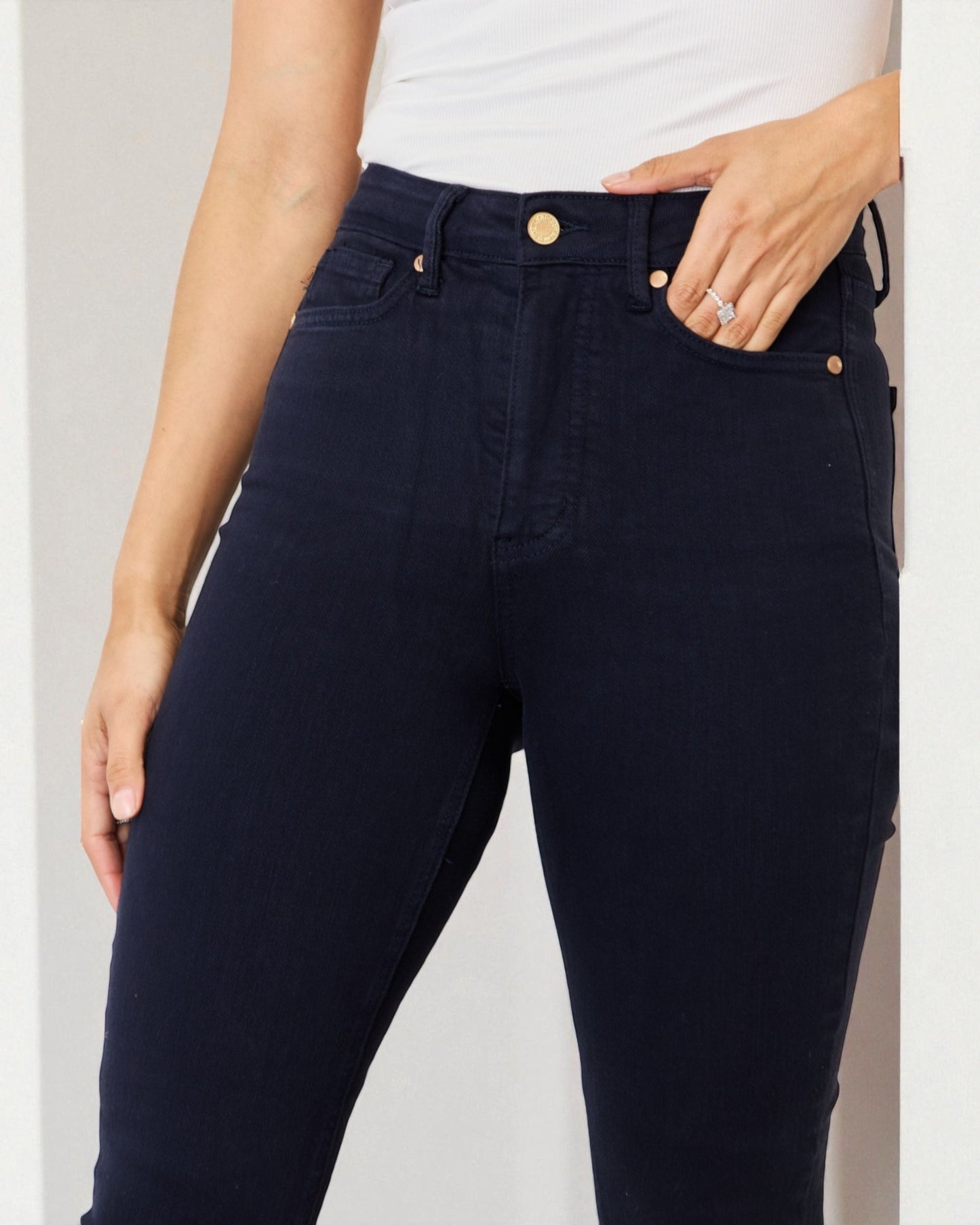 Person wearing navy blue jeans with a white background