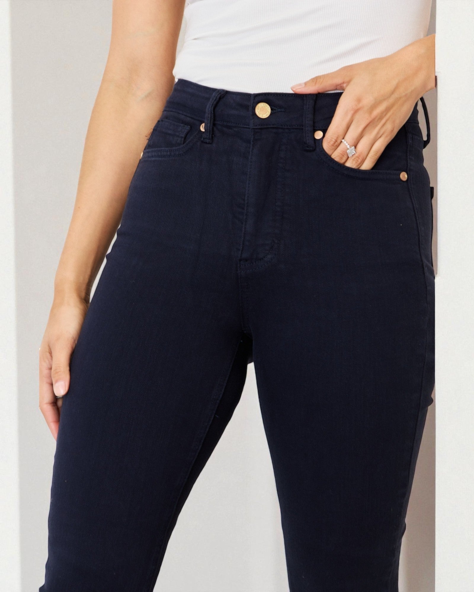 Person wearing navy blue jeans with a white background