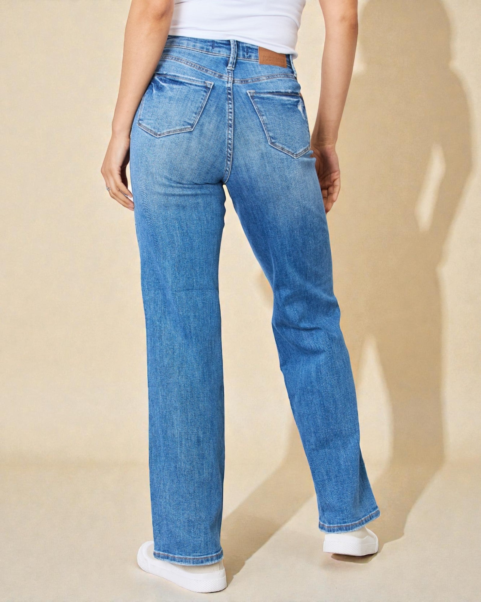 Person wearing blue jeans on a beige background