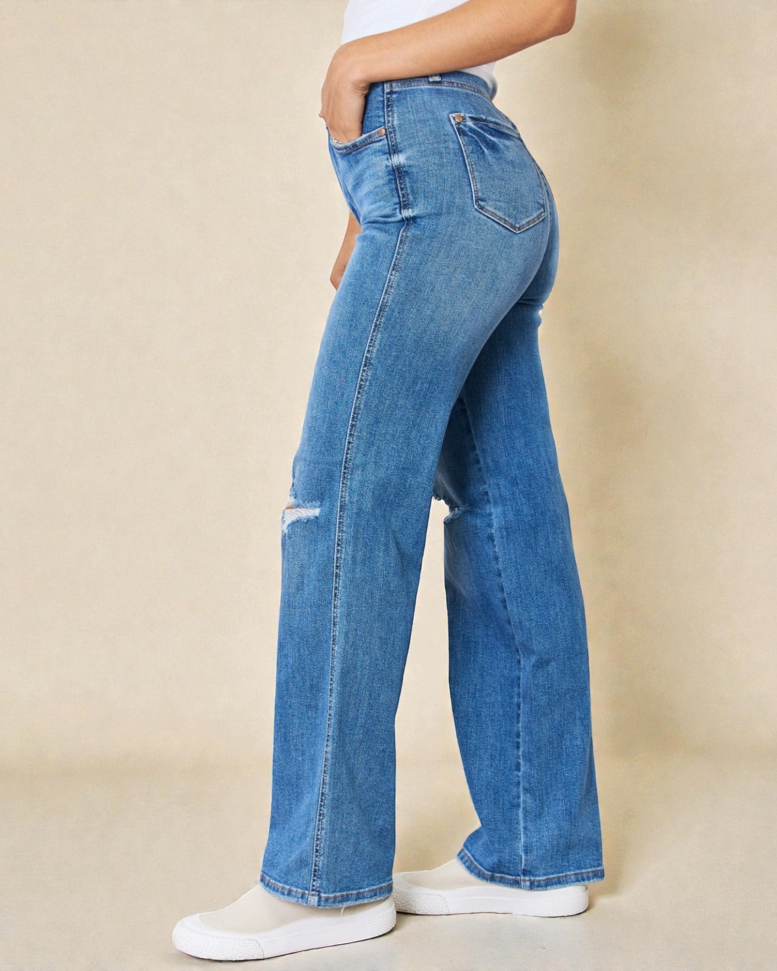 Blue jeans worn by a person on a beige background