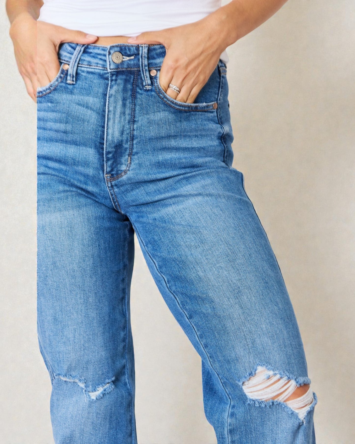 Person wearing blue jeans with a plain background