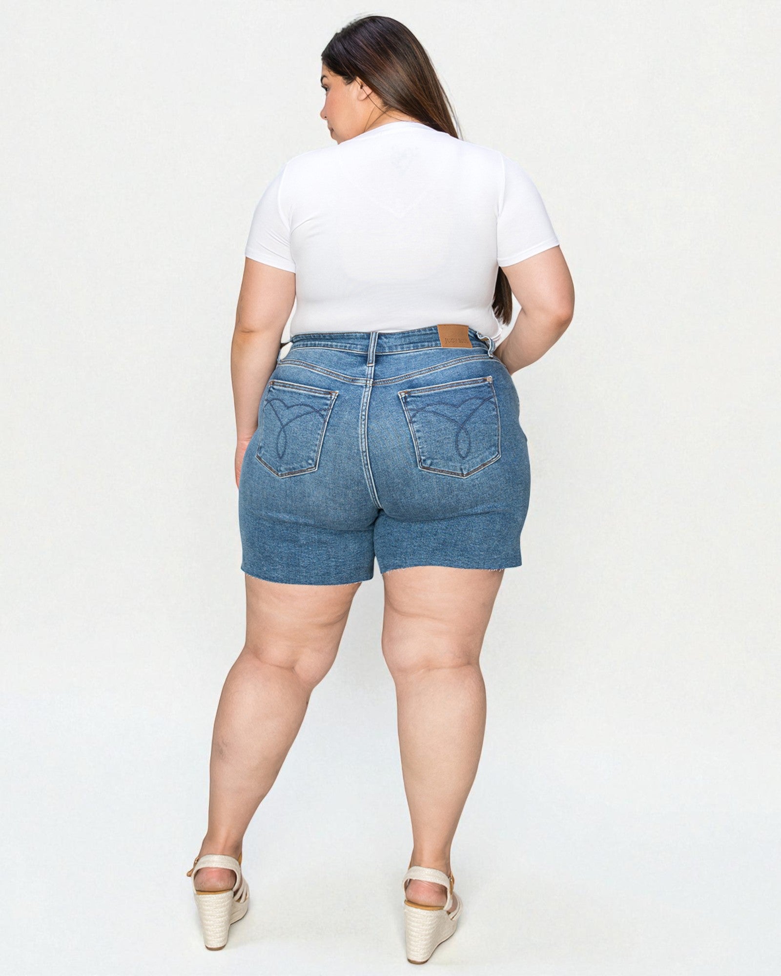 Person wearing blue denim shorts and a white t-shirt on a plain background