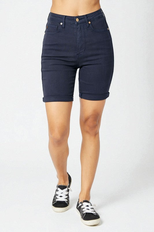 Navy blue denim shorts worn by a person on a white background