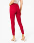 A model shown from the back wearing bright red skinny jeans, a white patterned top, and beige block-heel mule sandals against a plain white studio background.