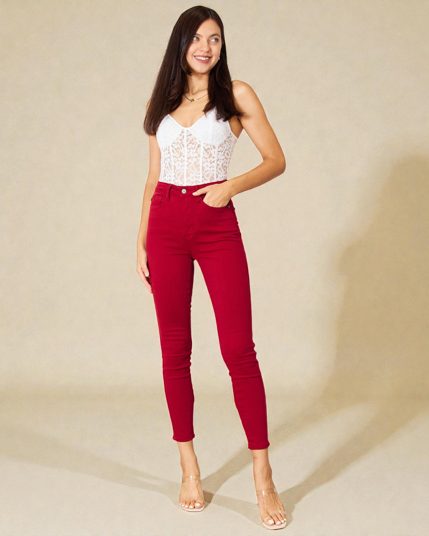 Woman wearing red pants and a white top against a beige background