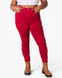 A model wearing bright red high-waisted skinny jeans with a ruched side detail, paired with a white crop top and brown platform ankle boots, against a plain white background.