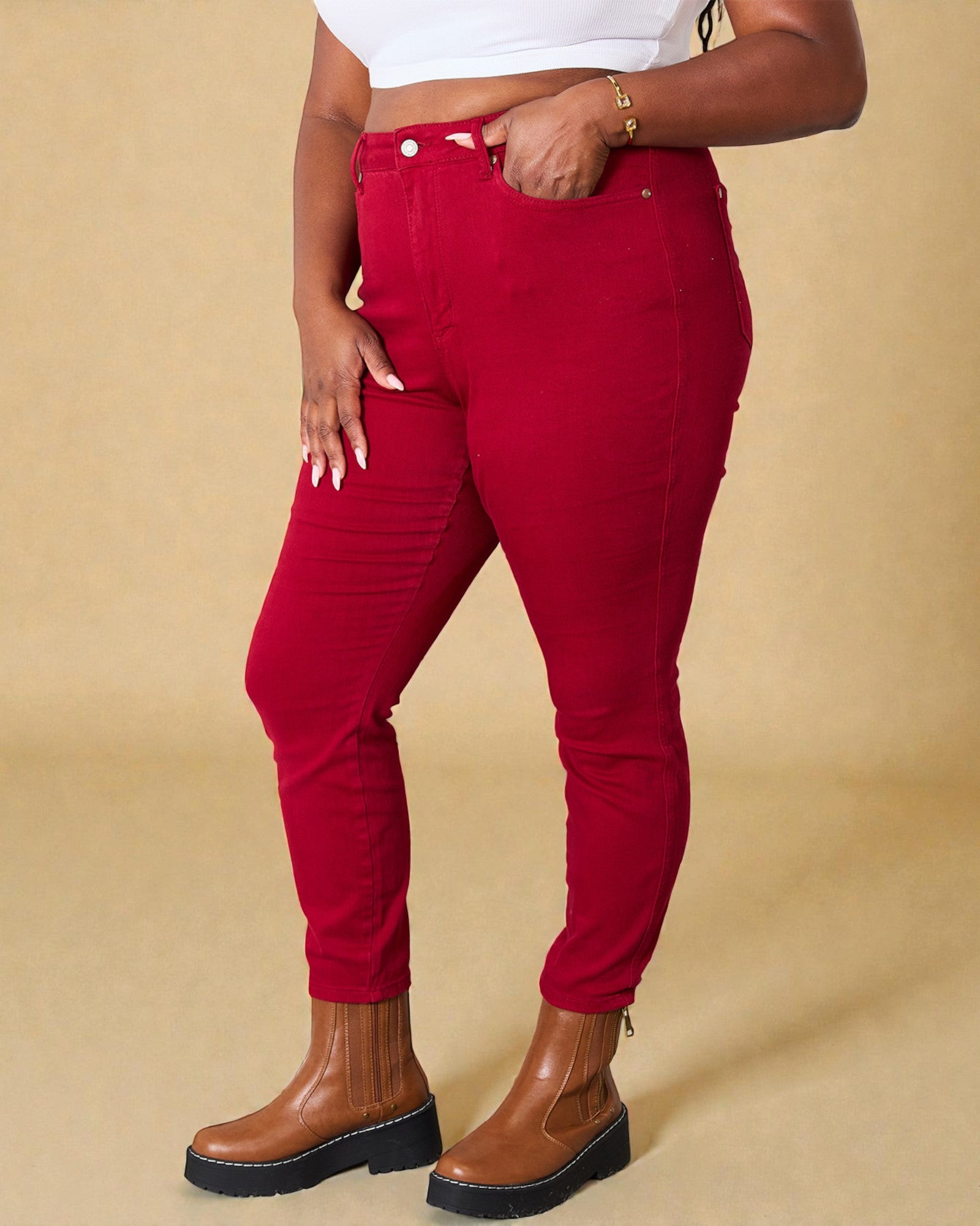 Person wearing red pants and brown boots on a beige background