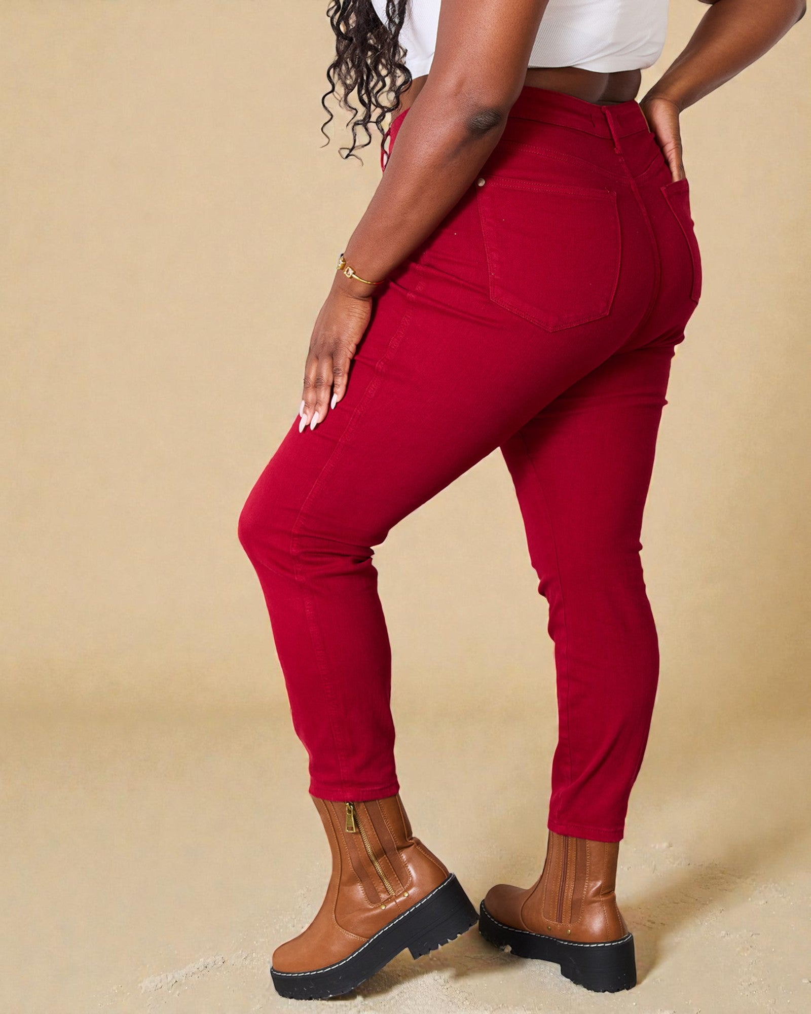 Person wearing red pants and brown boots on a beige background