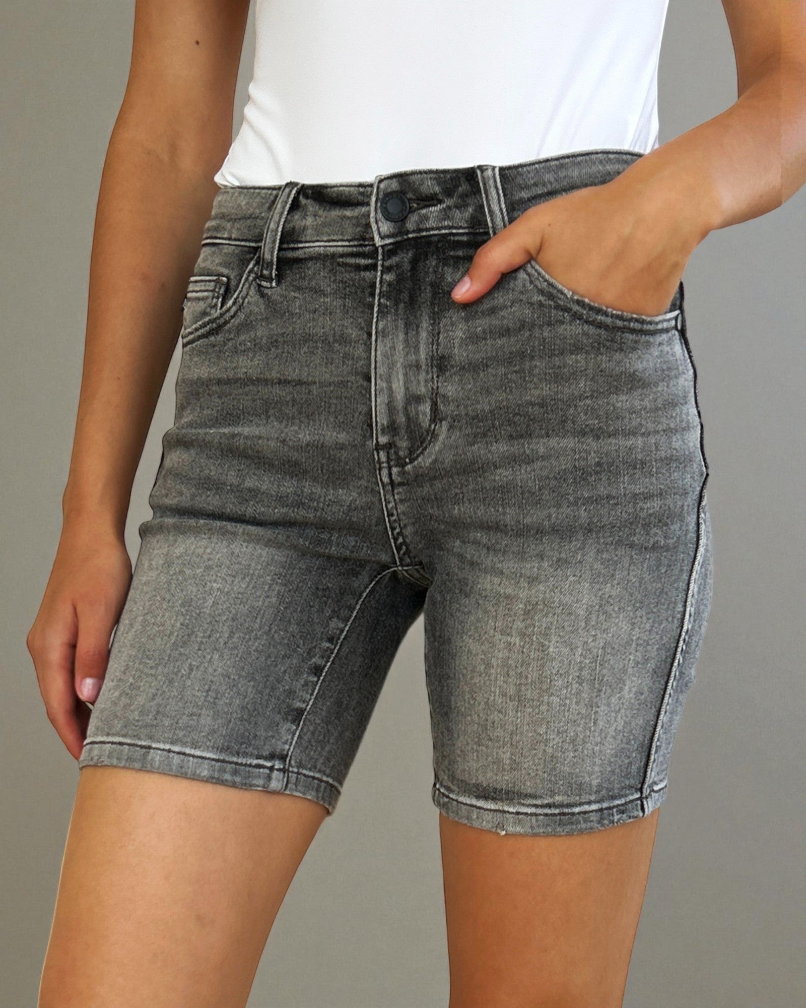 Person wearing gray denim shorts on a neutral background