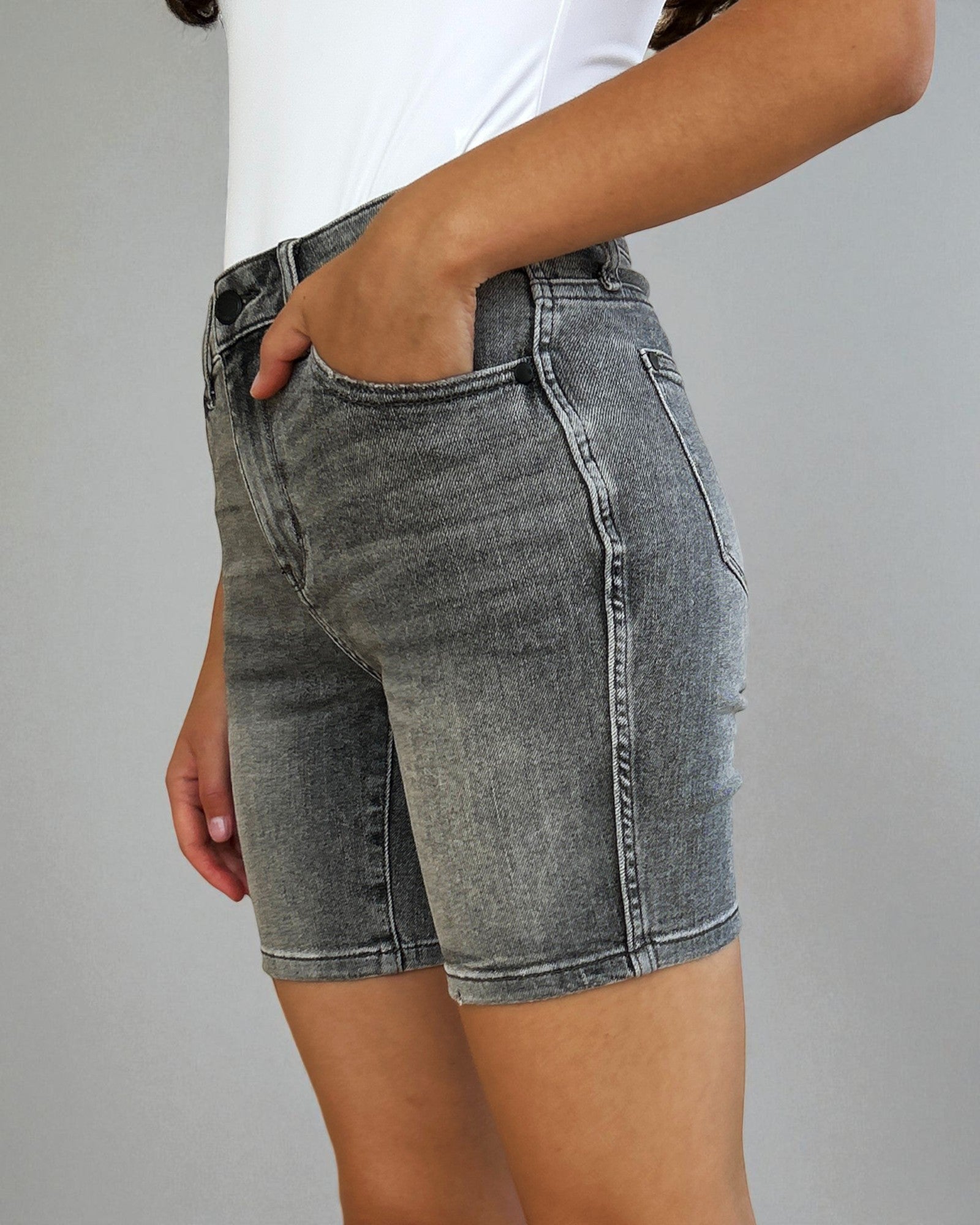 Person wearing gray denim shorts on a plain background