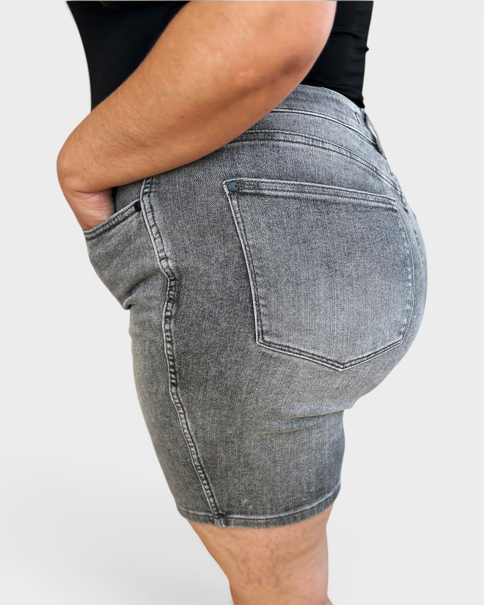 Person wearing gray denim shorts on a plain background