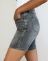 Denim shorts worn by a person on a plain background