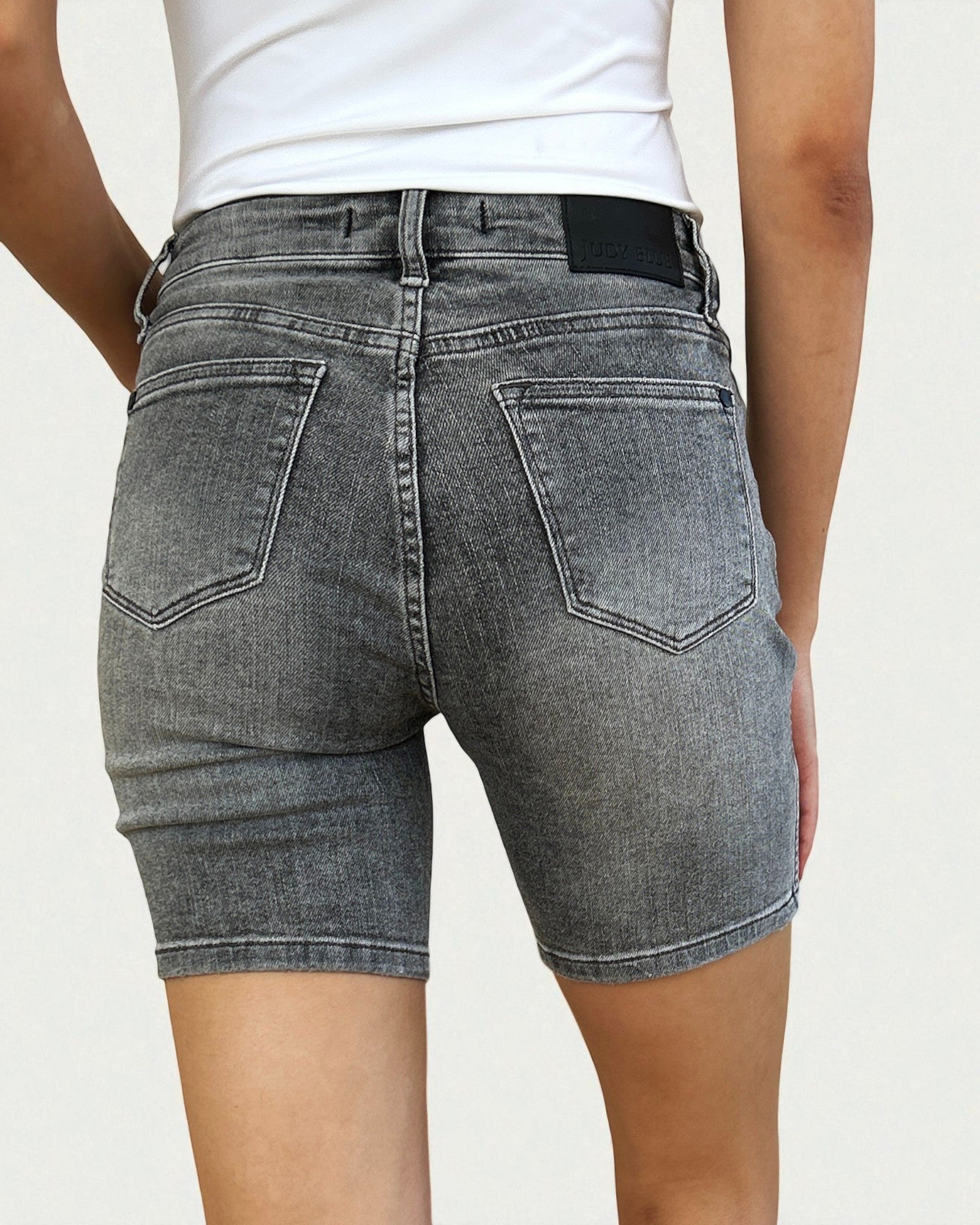 Person wearing gray denim shorts on a plain background
