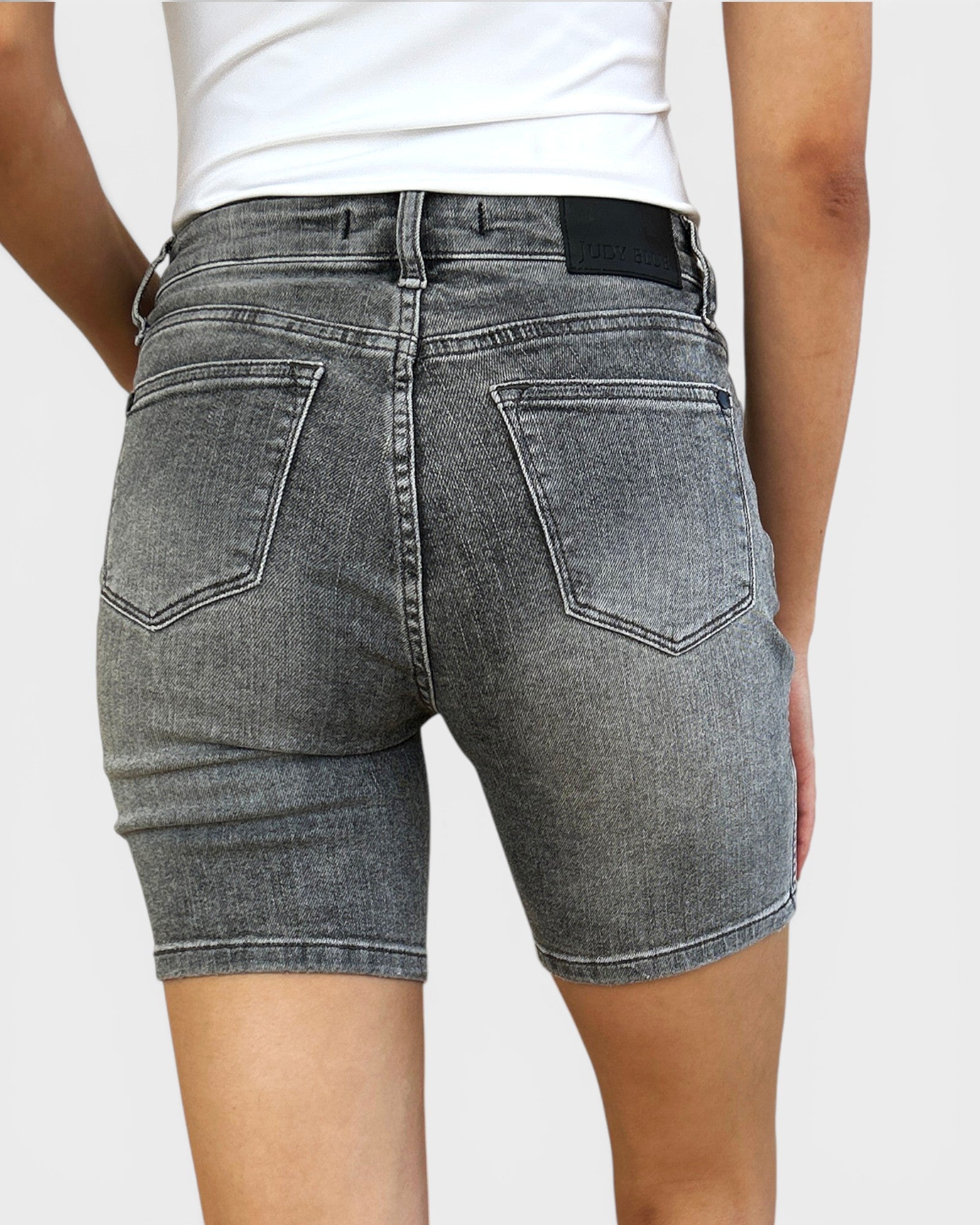 Person wearing gray denim shorts on a plain background