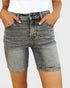 Person wearing gray denim shorts on a plain background