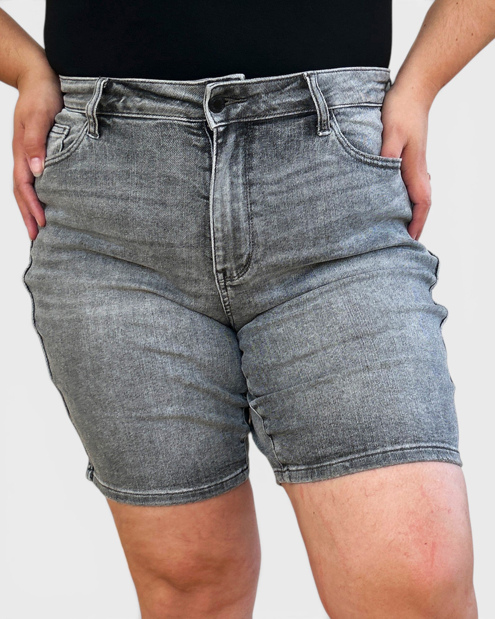 Person wearing gray denim shorts on a plain background