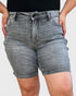 Person wearing gray denim shorts on a plain background