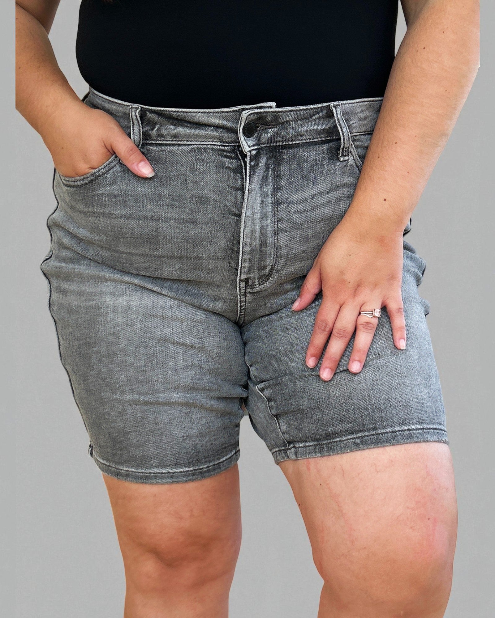 Person wearing gray denim shorts on a gray background