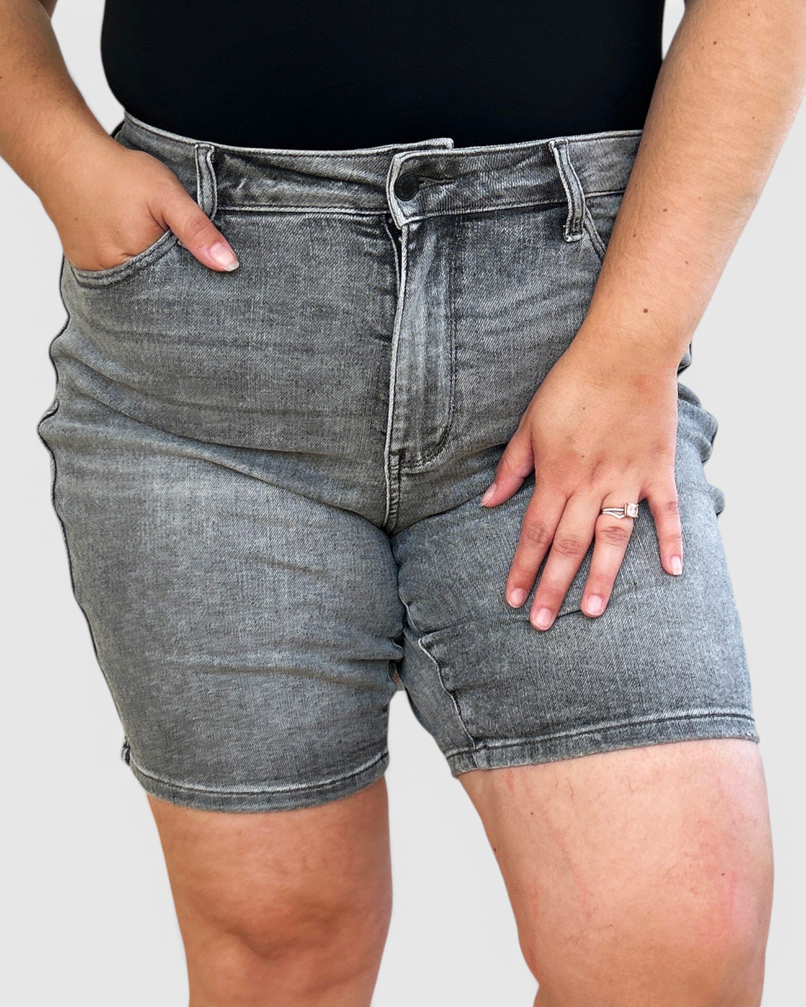 Person wearing gray denim shorts on a plain background
