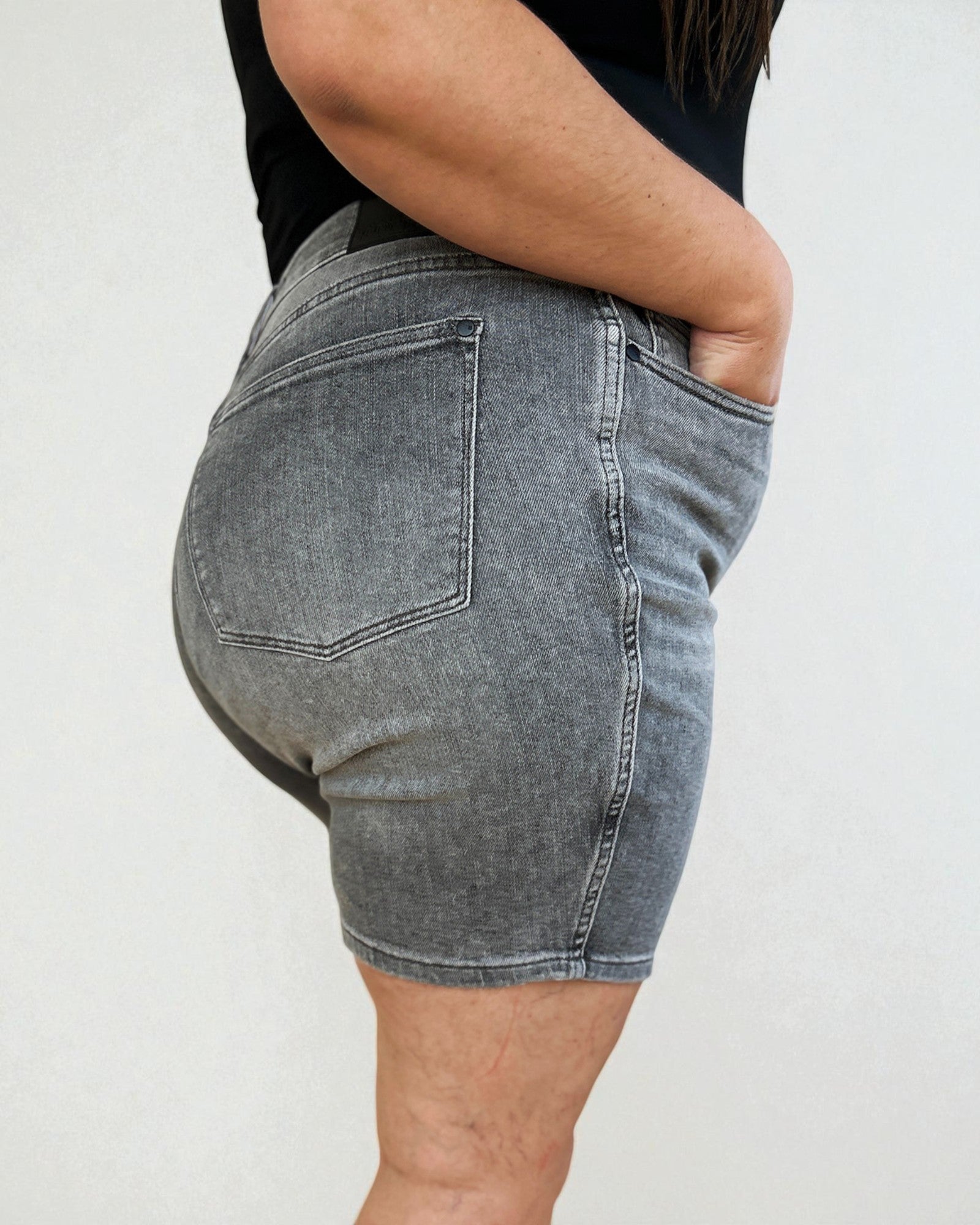 Person wearing gray denim shorts on a plain background