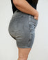 Person wearing gray denim shorts on a plain background