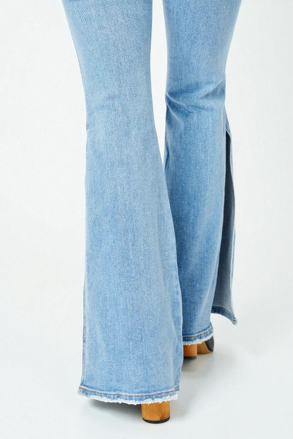Light blue flared jeans with a slit on a white background