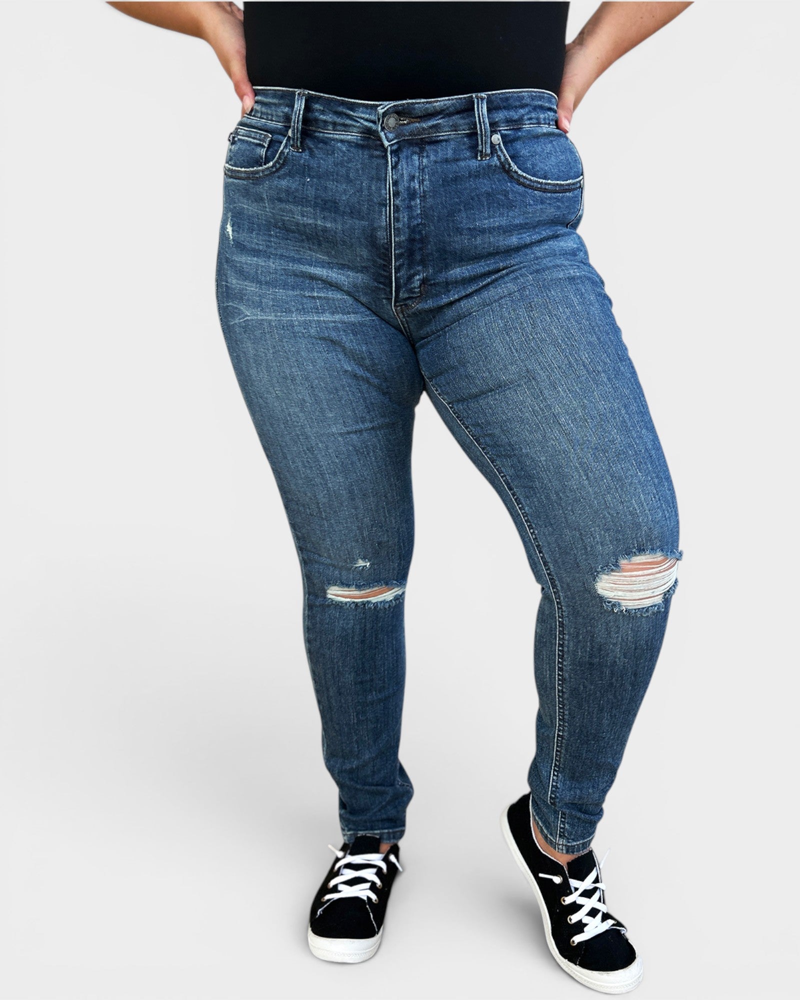 Person wearing blue jeans with slight distressing on a white background