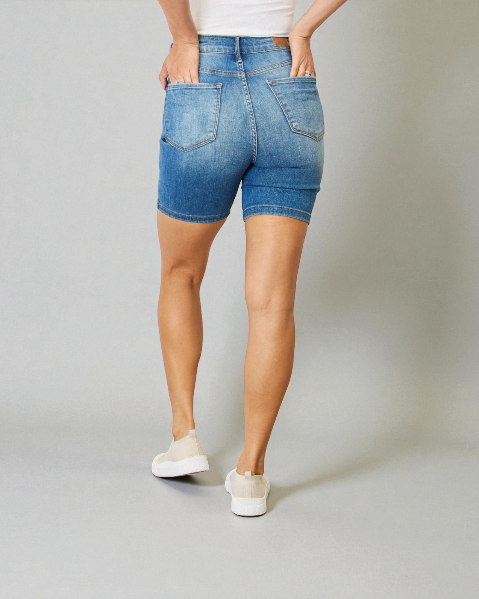 Person wearing blue denim shorts on a plain background