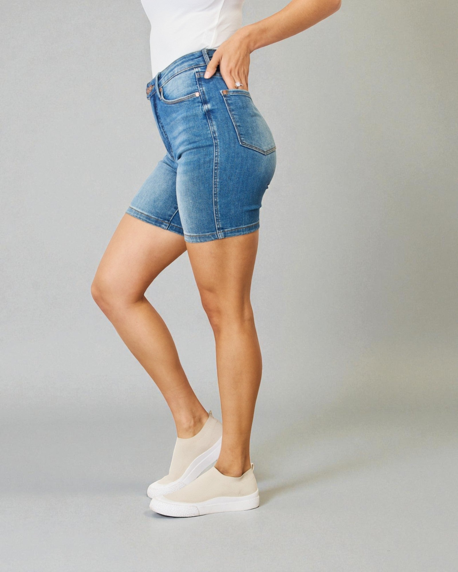 Person wearing blue denim shorts on a plain background